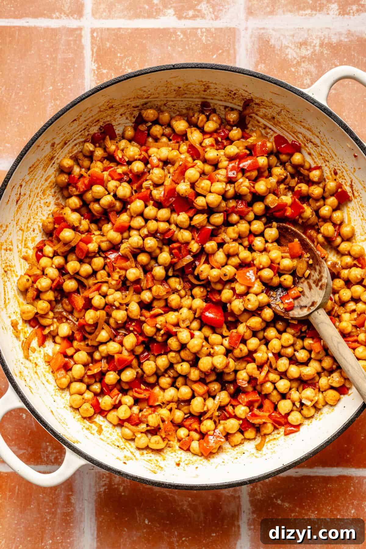 Chickpeas and other ingredients in a white skillet.