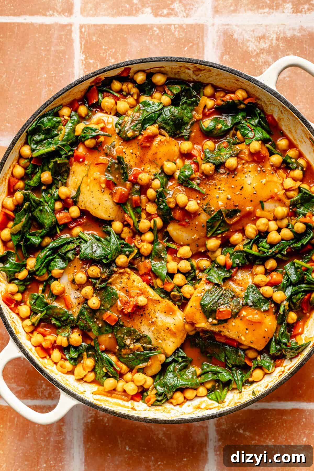 Spanish-Inspired Simmered White Fish in skillet. Fish and spinach added.