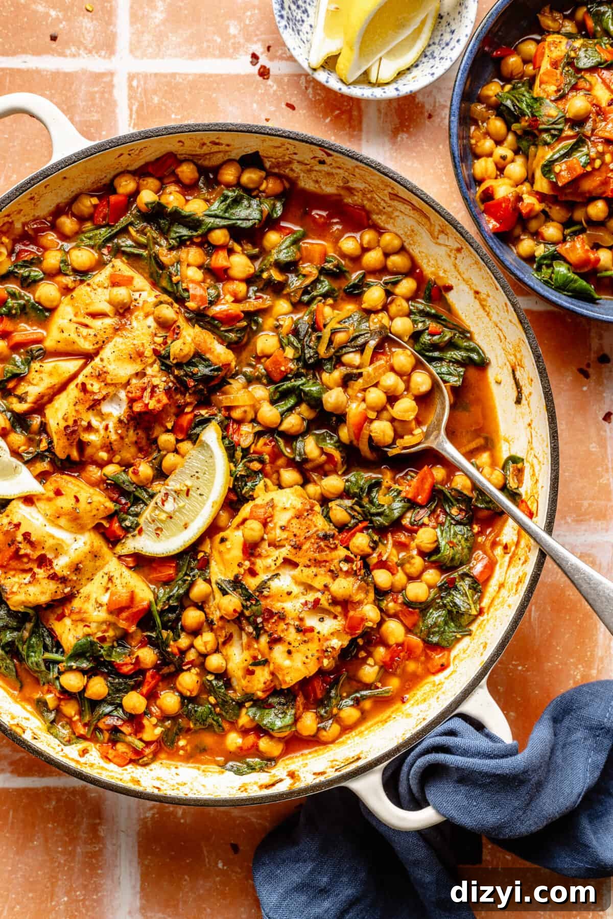 Spanish-Inspired Simmered White Fish in white skillet on tiled counter.