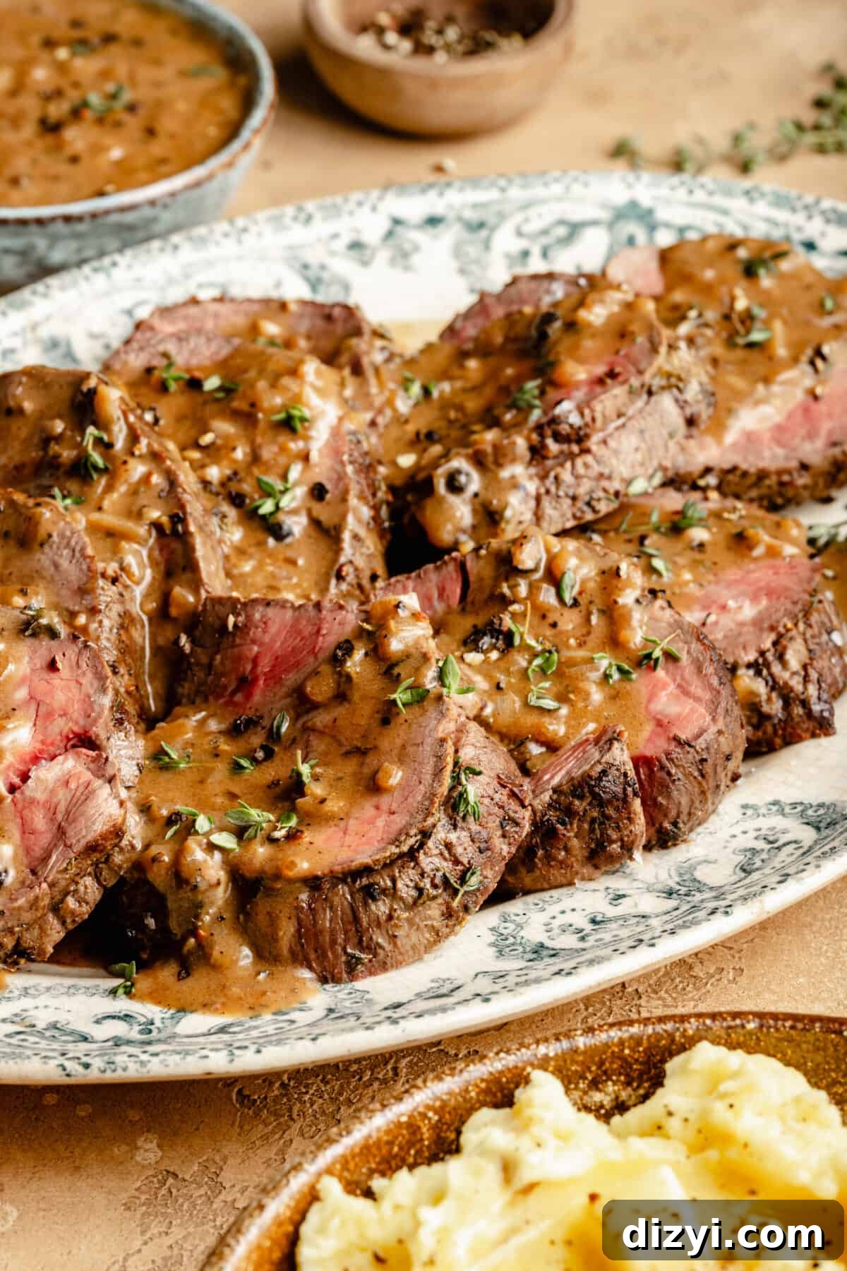 Close up of Beef Tenderloin sliced on large oval platter with Au Poivre on top.
