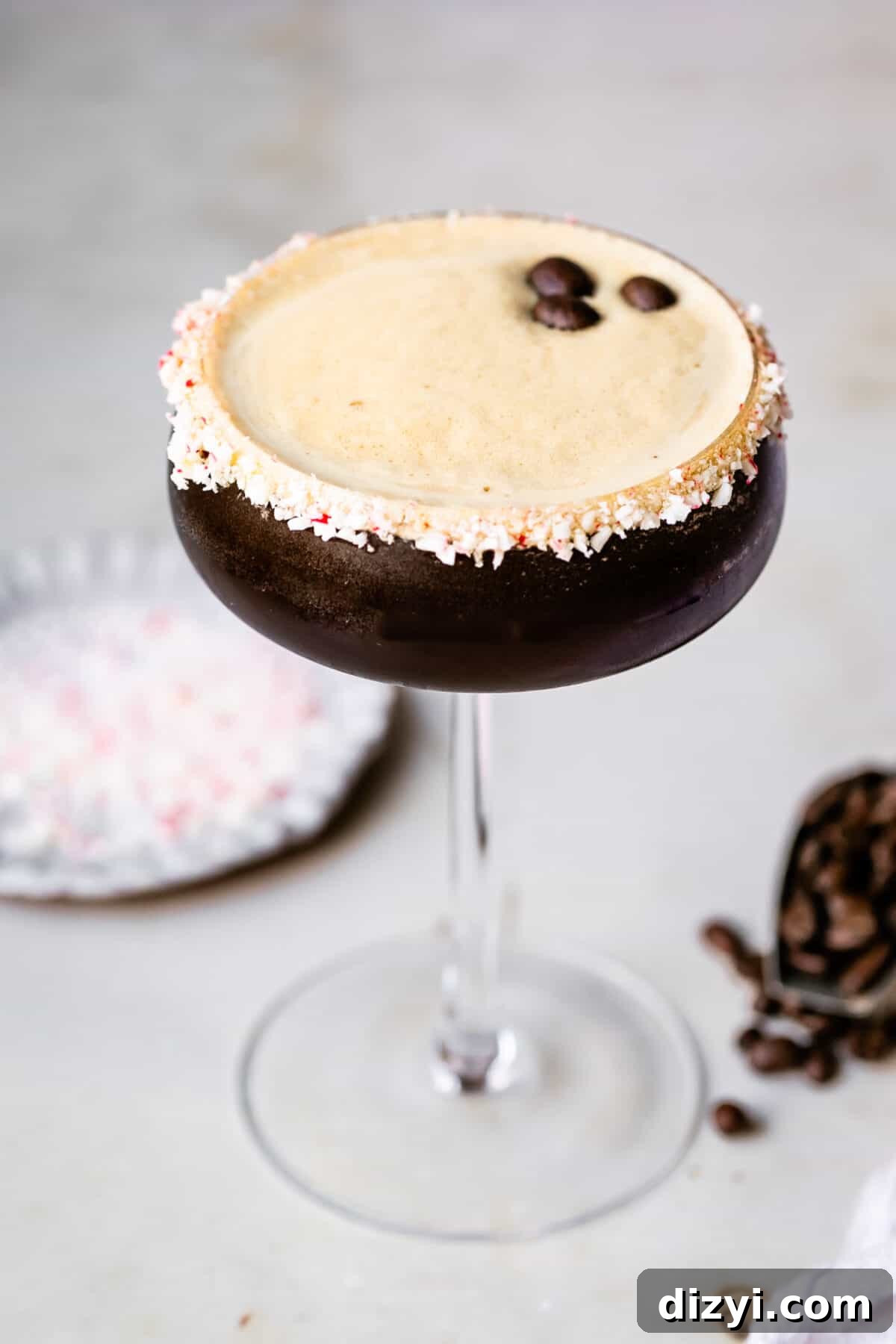 Peppermint Espresso Martini Recipe 2 Peppermint Espresso Martini in a tall glass. Espresso beans and crushed peppermint in the background.