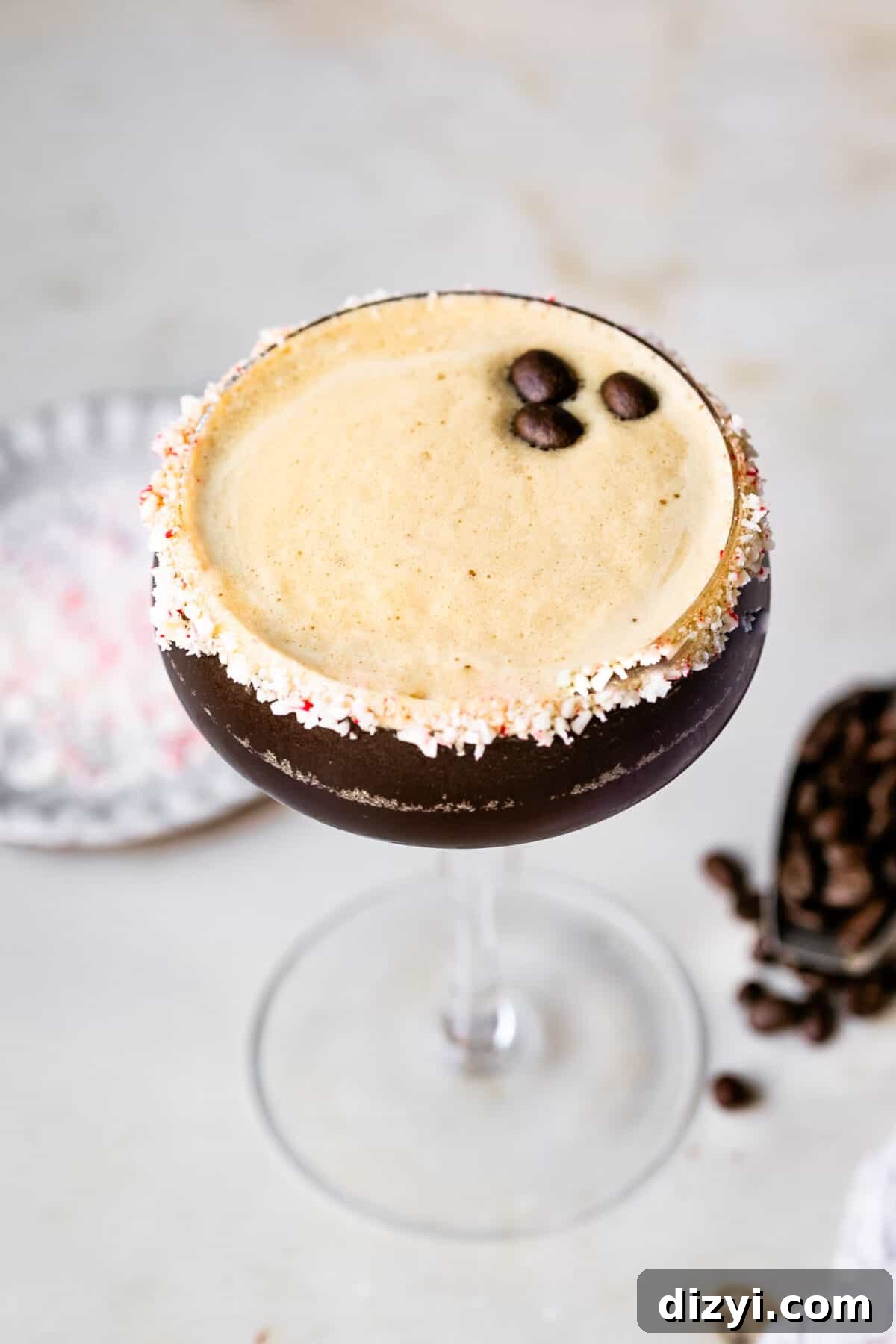 Peppermint Espresso Martini Recipe 3 Peppermint Espresso Martini in a tall glass. Espresso beans and crushed peppermint in the background.