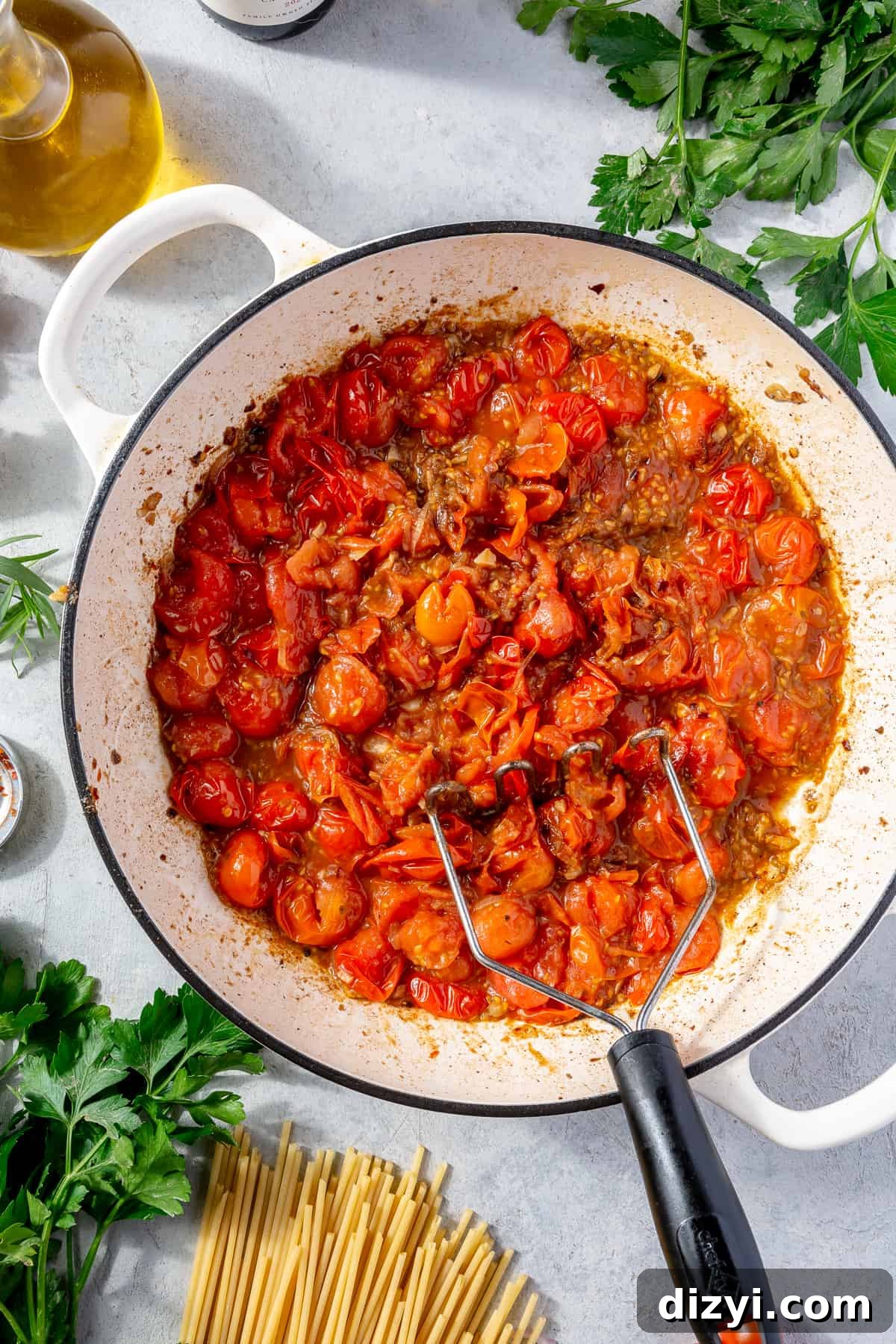 Cherry tomatoes in skillet with anchovy mixture. Tomatoes slightly mashed.