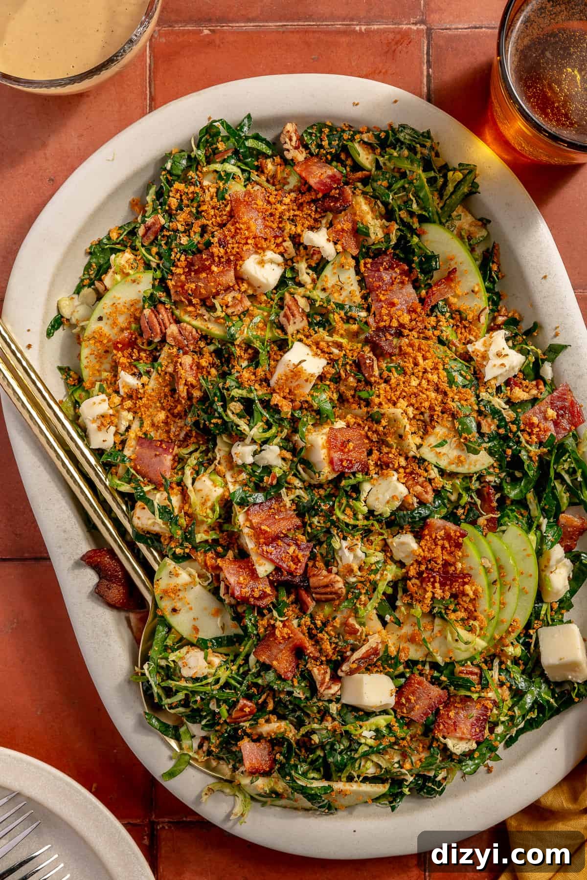 Bacon Brussels Crunch Salad on a large white platter. Serving utensils in the salad.