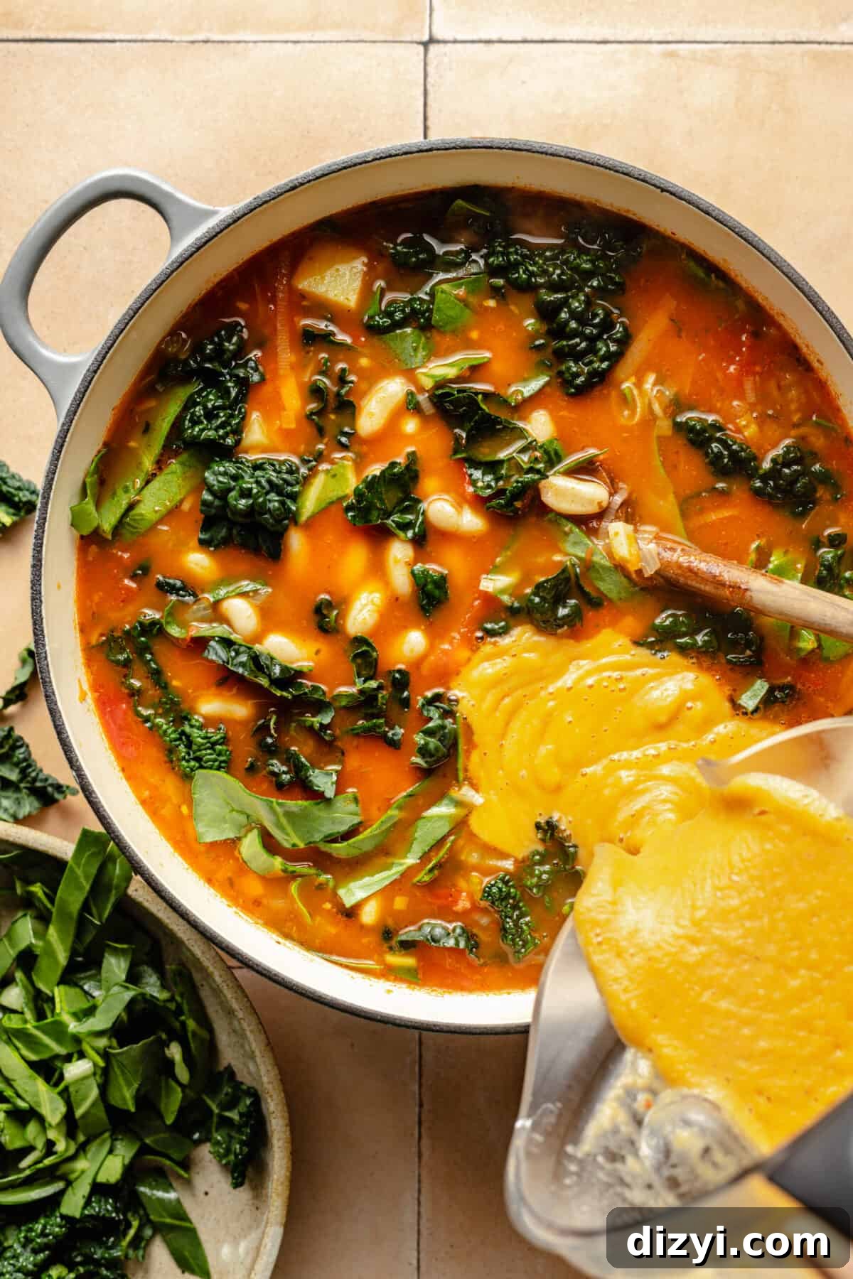Tuscan Ribollita in dutch oven with blended portion being poured in.