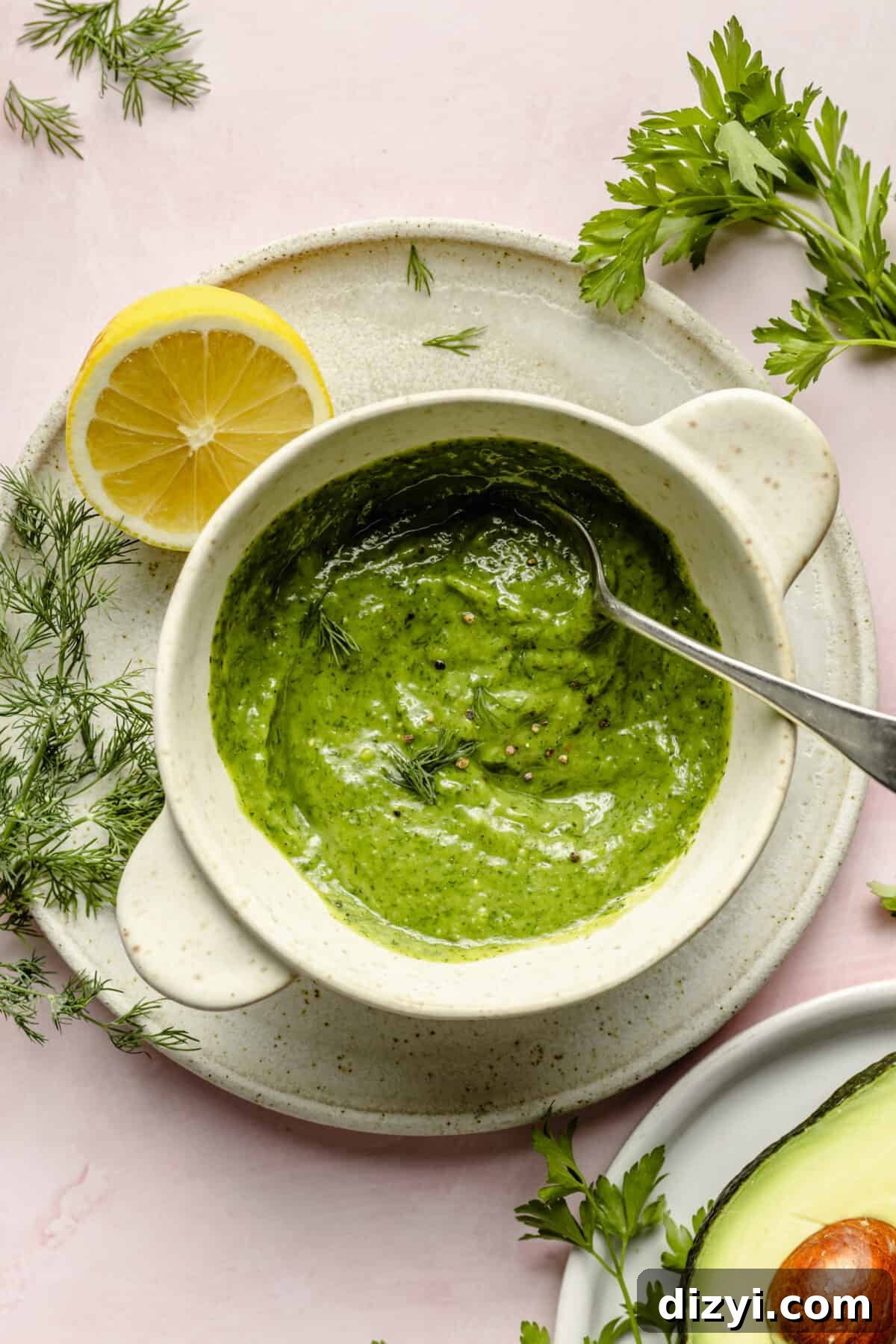 Dressing for cucumber salad in a small bowl with lemon and other garnishes scattered around.