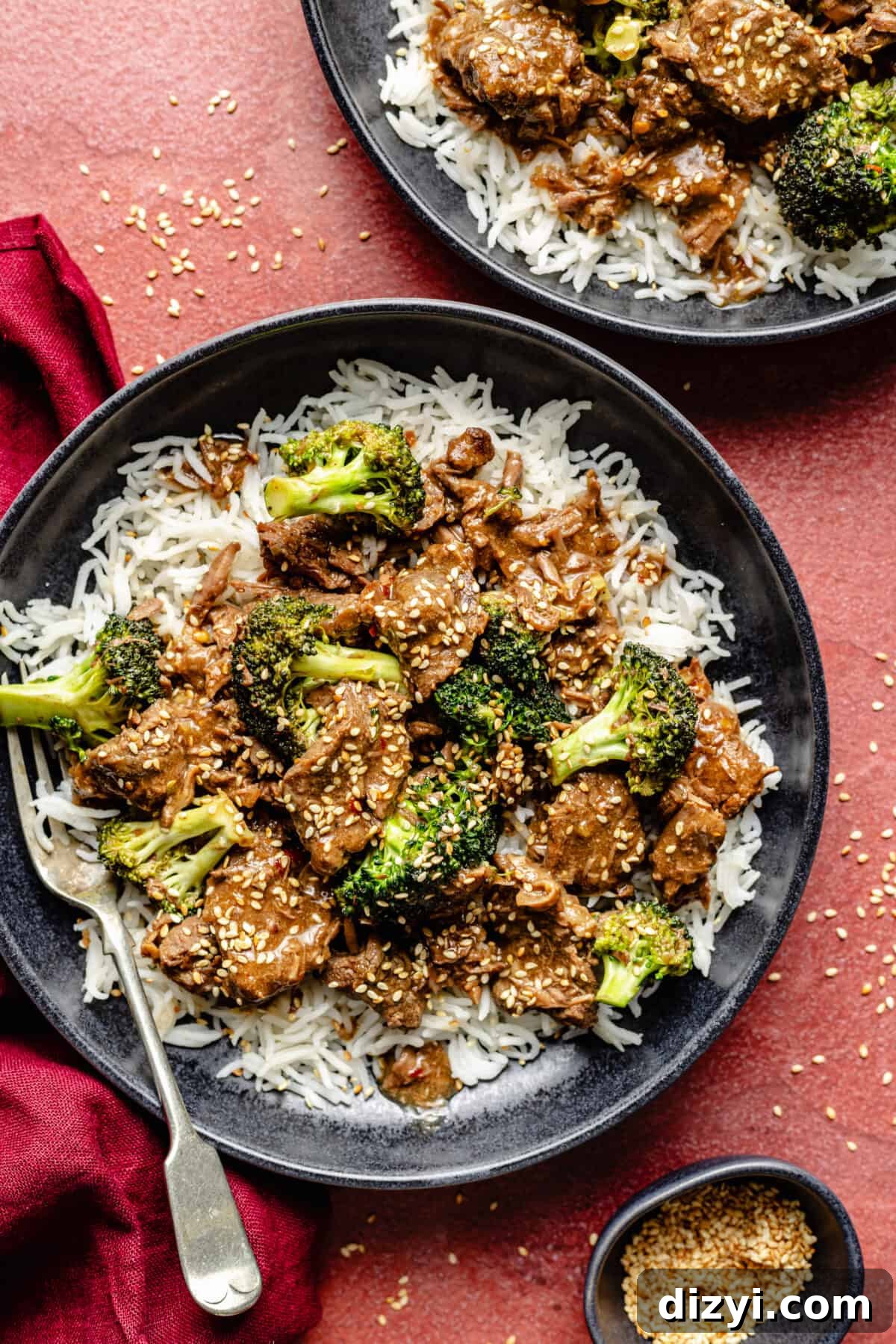 Slow Cooker Beef and Broccoli in bowls on red background.