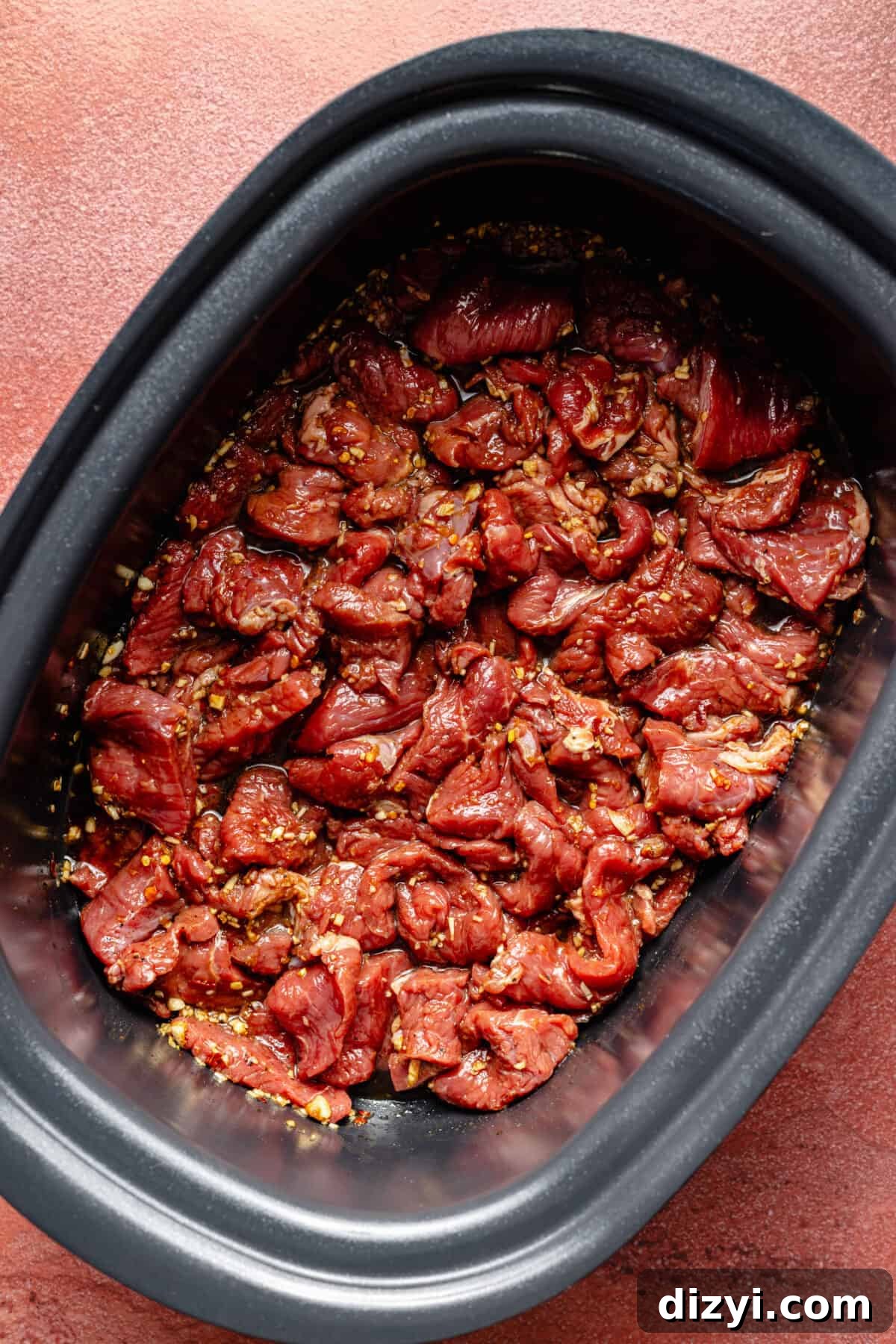 Sliced beef and sauce in slow cooker.