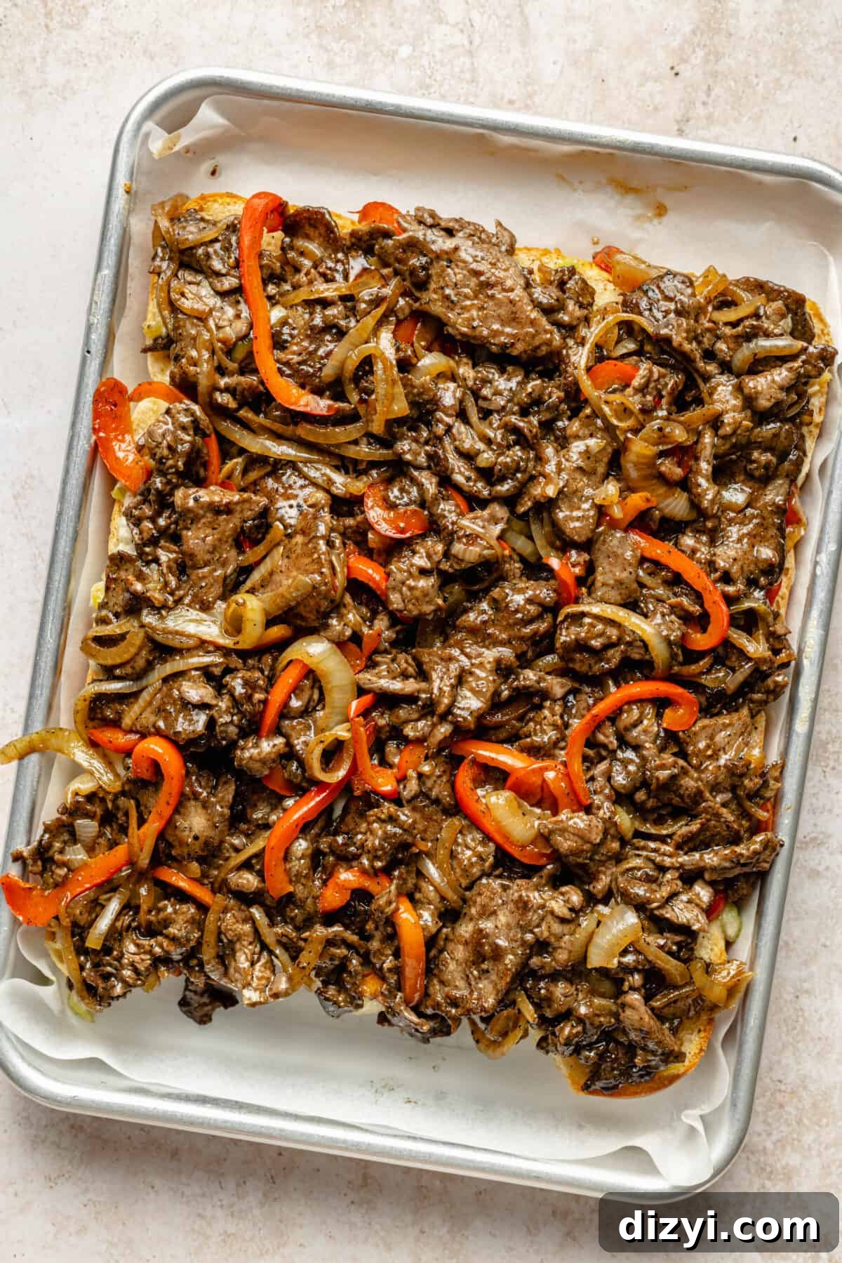 Rolls on sheet pan with steak and veggie mixture on top.