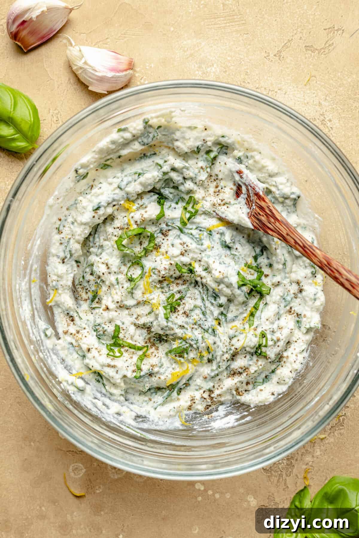 Ricotta mixture in a glass bowl with a wooden spoon.
