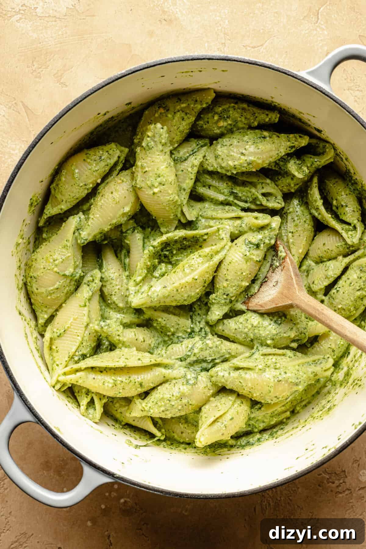 Cooked pasta shells in a pot, coated in pesto mixture.