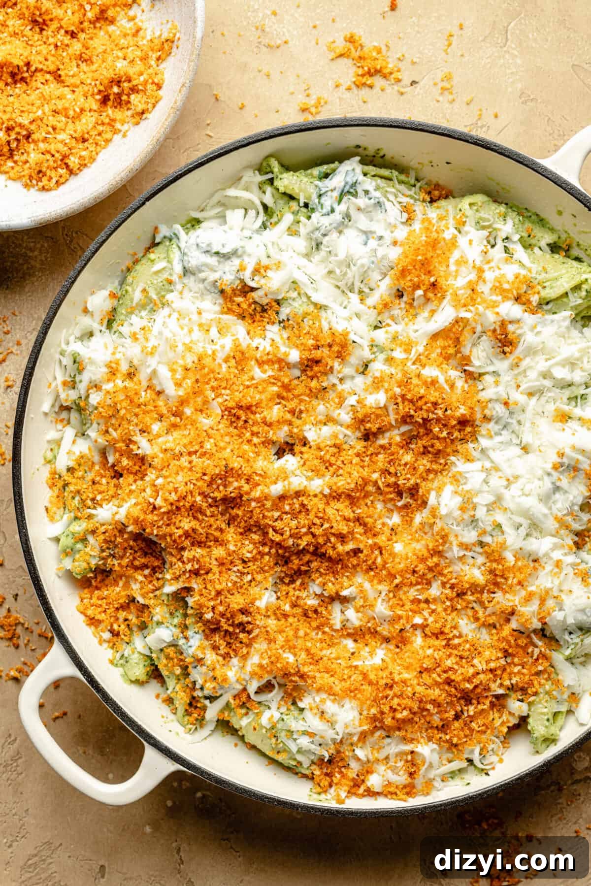 Pesto unstuffed shells assembled in a skillet, ready to bake.