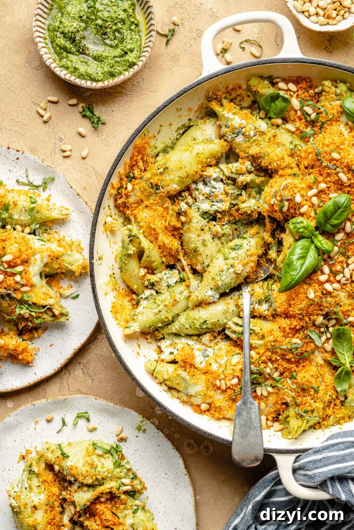 Pesto unstuffed shells in a braiser; spoon scooping pasta out.