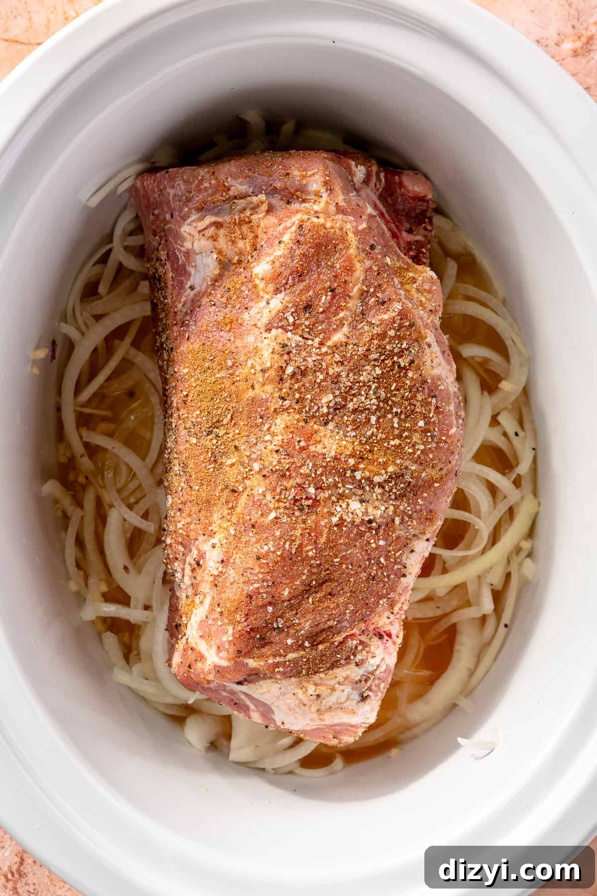Raw pork in slow cooker over onions.
