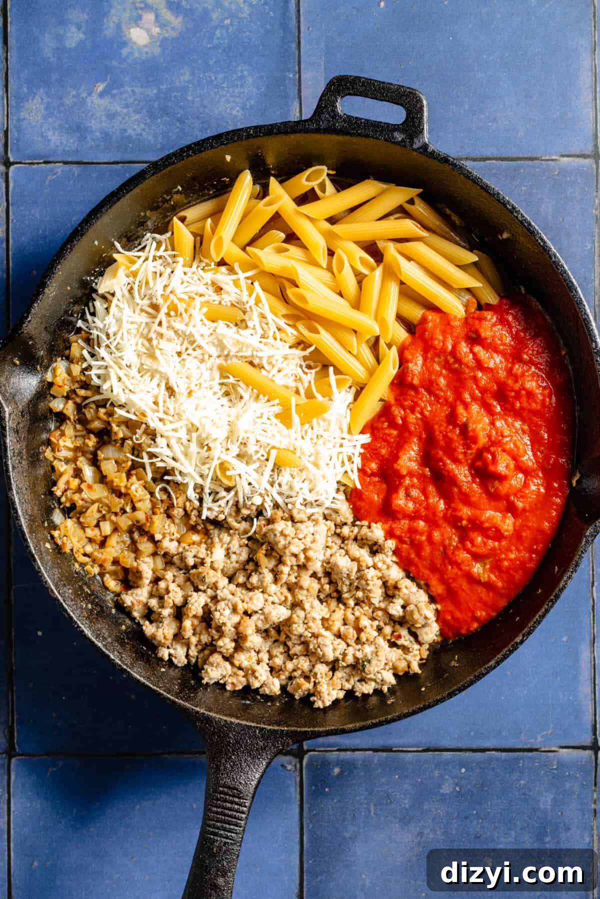 Skillet Pizza Penne: Cheesy One-Pan Pasta 4 Cast iron skillet with dried pasta, sauce, cheese, ground sausage.