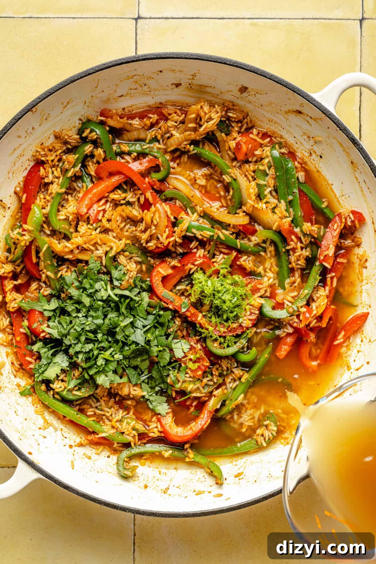 Herbs, rice, broth, peppers, and onion in a skillet.
