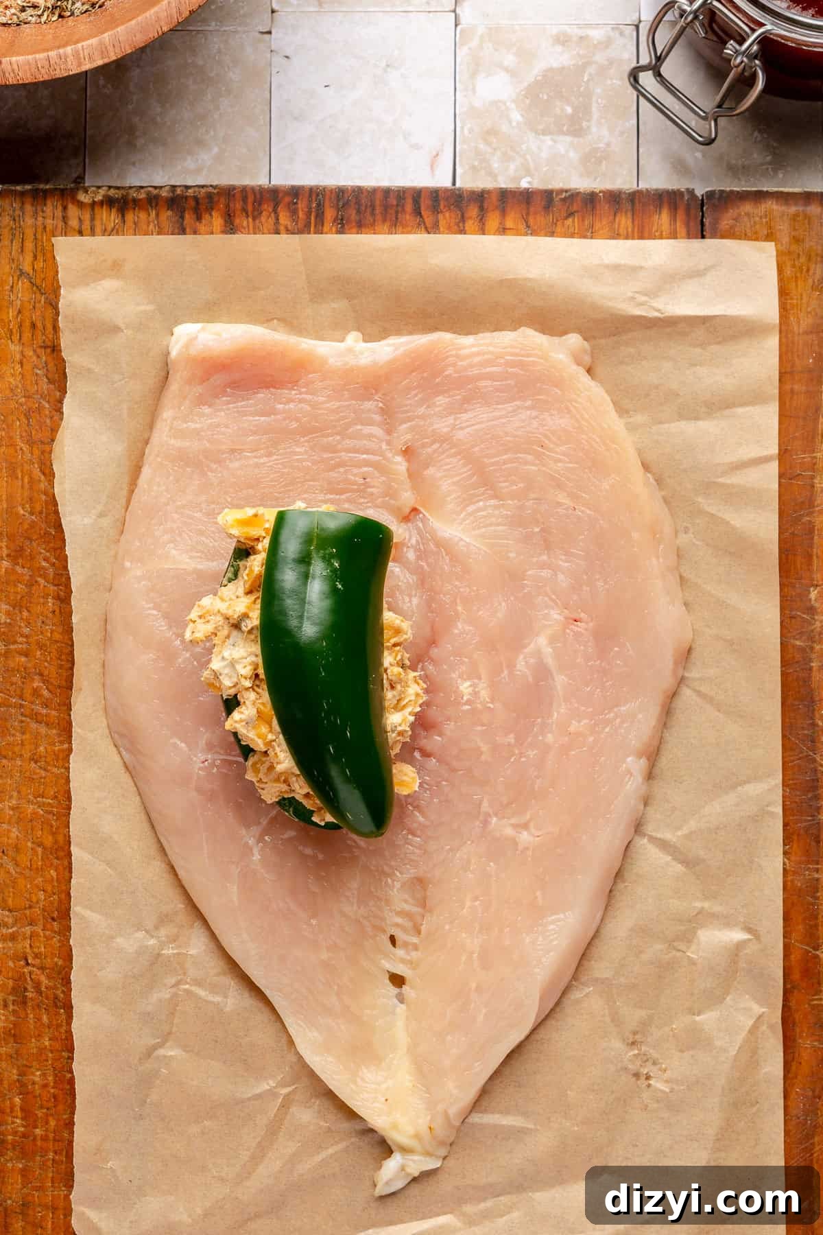 Chicken breast on cutting board stuffed with jalepeno and cream cheese filling.