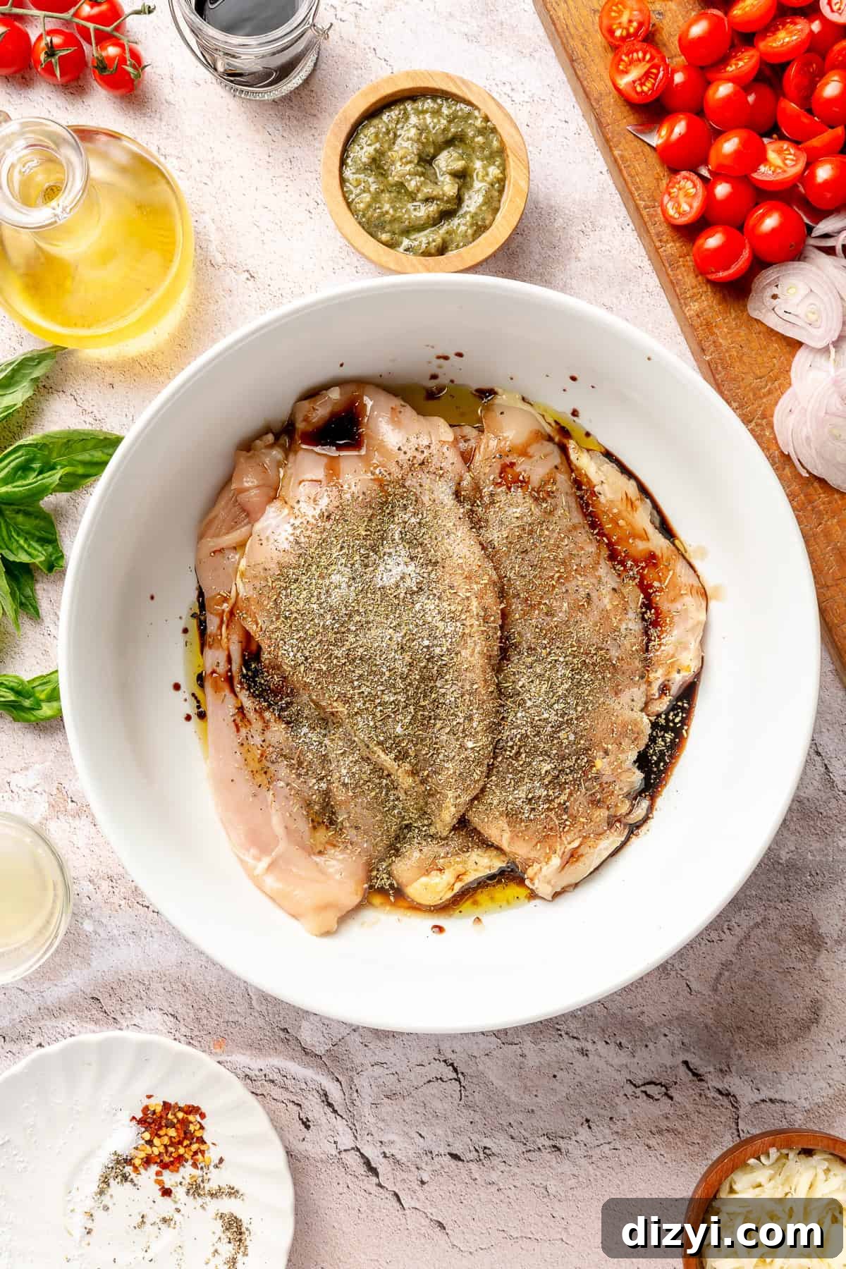 Raw chicken breasts marinating in large white bowl.