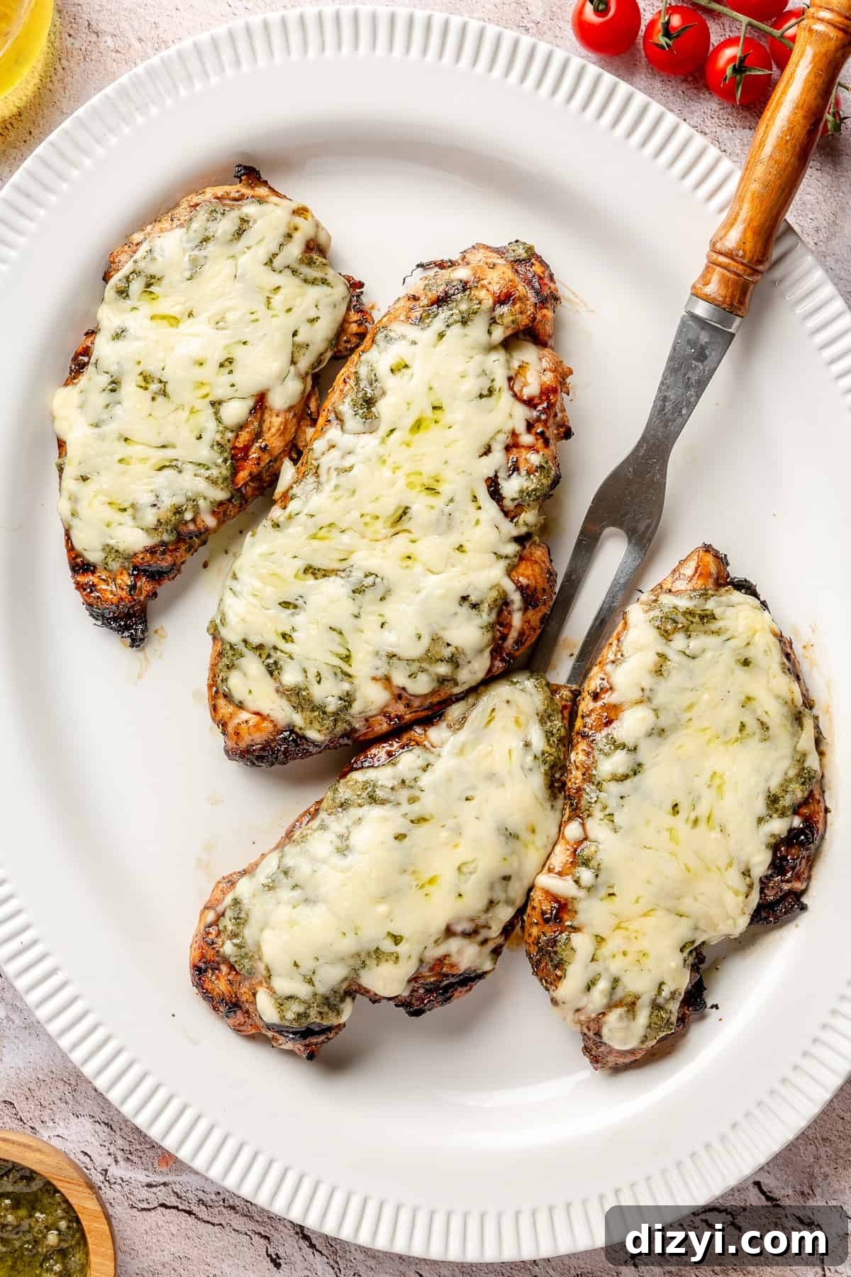 Grilled chicken breasts with cheese melted on top on white platter.