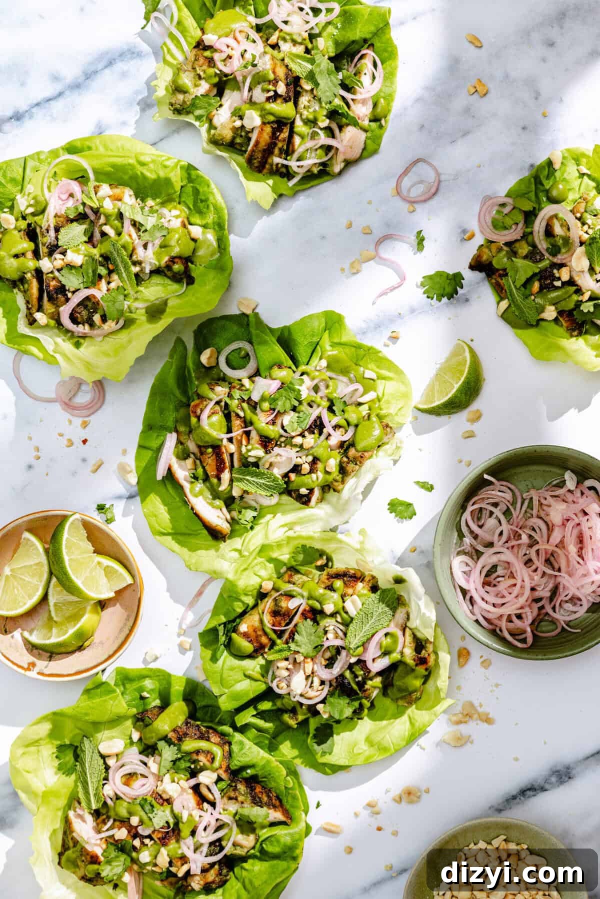 Spicy Coconut Grilled Chicken Lettuce Wraps assembled with additional limes and picked shallots surrounding.