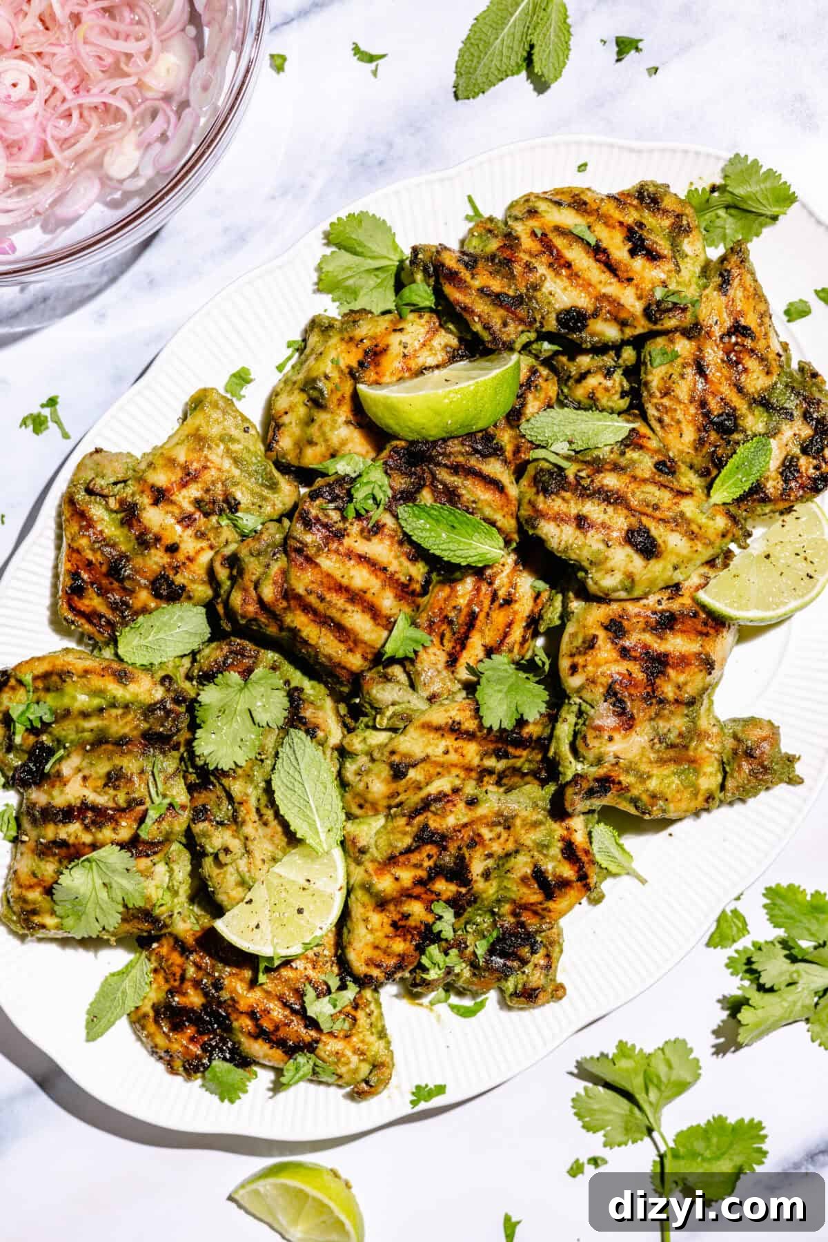 Spicy Coconut Grilled Chicken on large white platter with lime wedges and fresh cilantro.