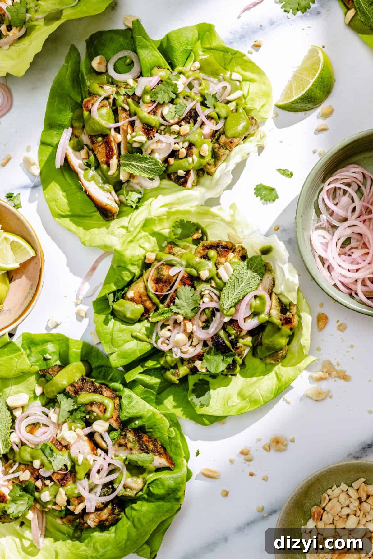 Spicy Coconut Grilled Chicken Lettuce Wraps assembled with additional limes and picked shallots surrounding.