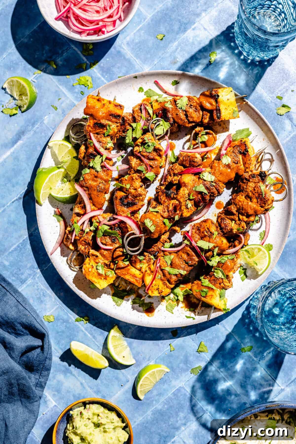 Pork Pastor Skewers assembled on plate. Limes and pickled onions scattered around.