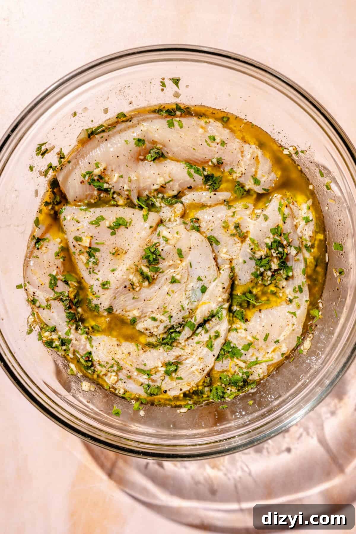 Raw chicken marinating in bowl for Giardiniera Chicken Melts.