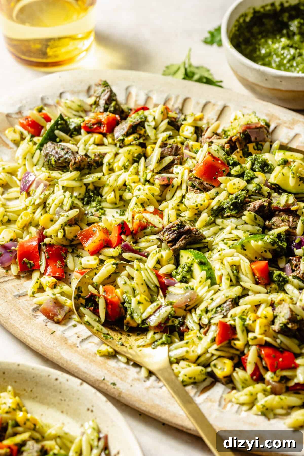 Grilled Steak and Chimichurri Pasta Salad on oval platter with spoon in it.