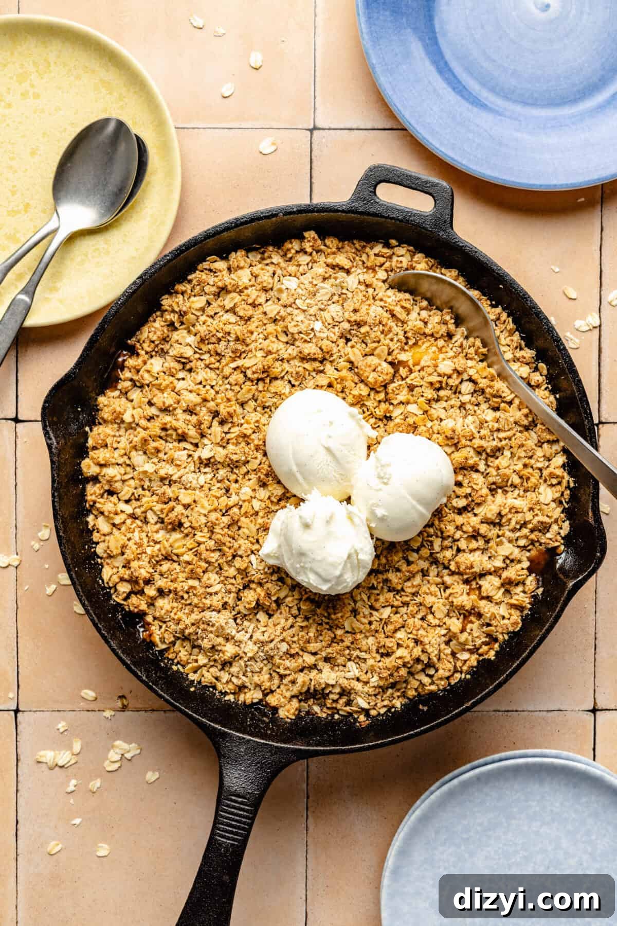 Simple Skillet Peach Crumble in black cast iron skillet with three scoops of vanilla ice cream on top.