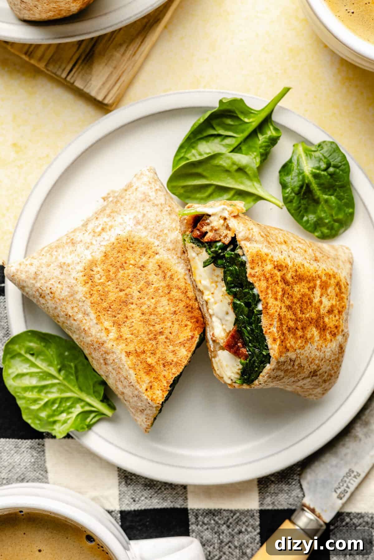 Copycat Starbucks Egg White Breakfast Wrap Recipe 4 Copycat Starbucks Egg White Breakfast Wrap sliced on plate. Spinach garnishing plate.