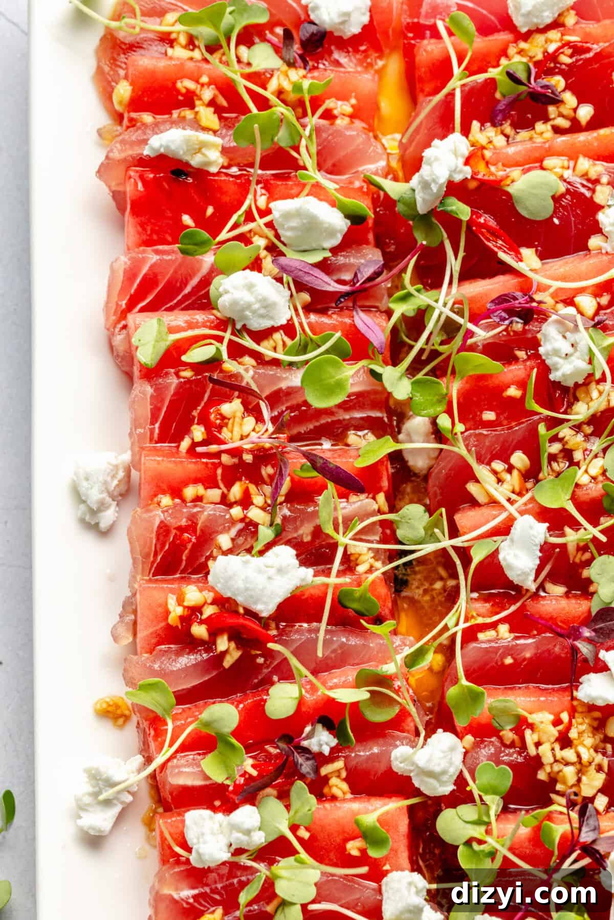 Watermelon and Tuna Sashimi Recipe 4 White platter with domino-size pieces of watermelon and ahi tuna layered, topped with microgreens and crumbled goat cheese.