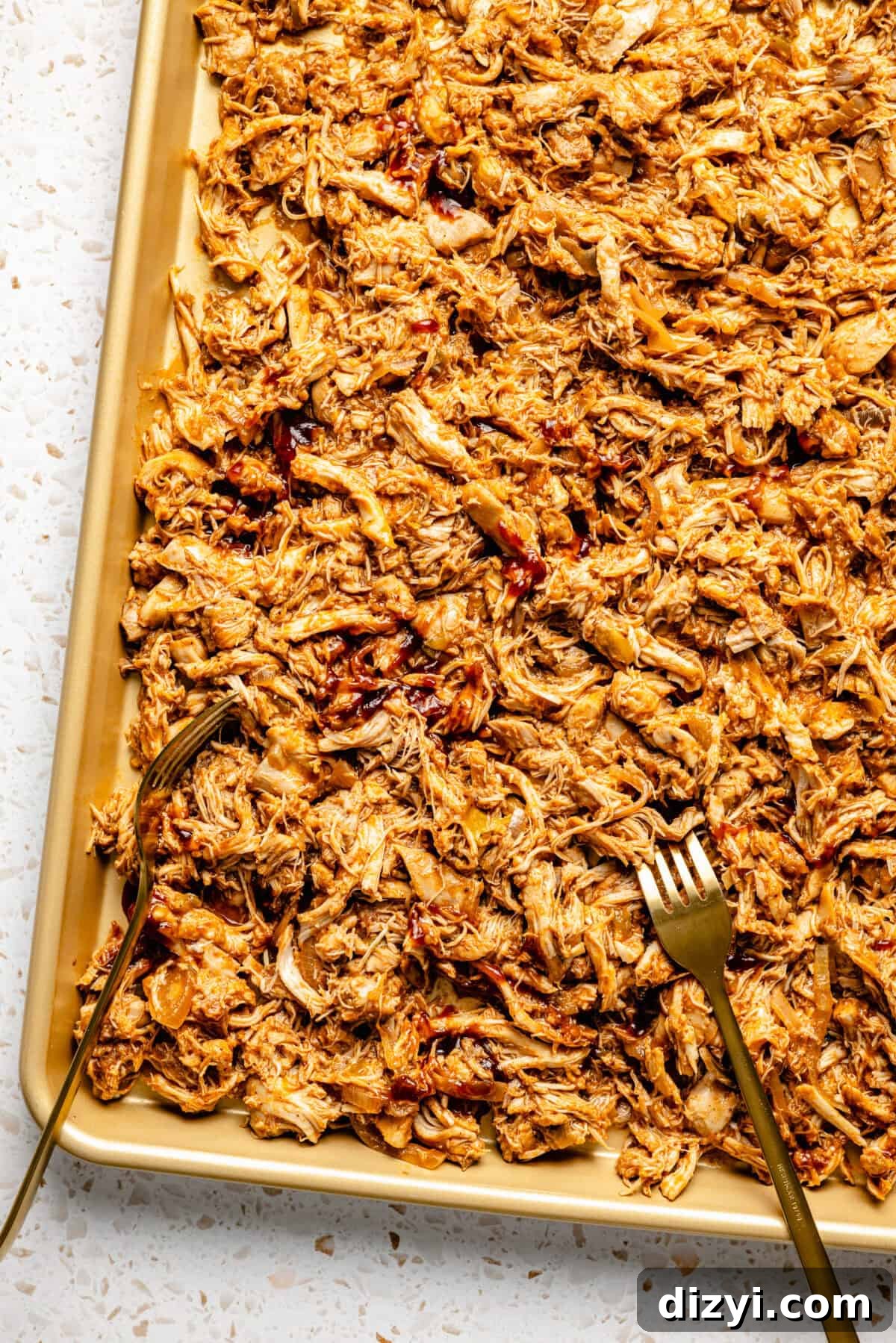 Slow Cooker BBQ Chicken Tacos with Shredded Chicken 4 Shredded Slow Cooker BBQ Chicken on a gold baking sheet, with 2 forks used to shred.