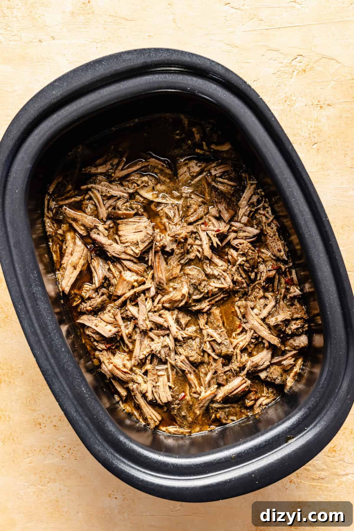 The beef, shredded, in the bottom of the slow cooker.