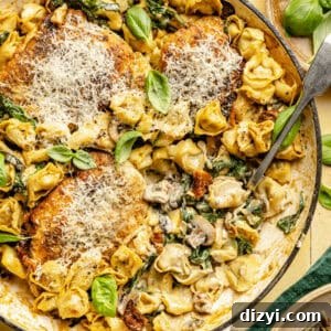 One-Pan Creamy Chicken and Tortellini Bake 6 A close-up shot of a pot of Creamy Spinach Chicken and Tortellini Bake on a yellow countertop. There is a serving spoon in the pot, a dark green napkin in the bottom right corner, as well as tan dishes.