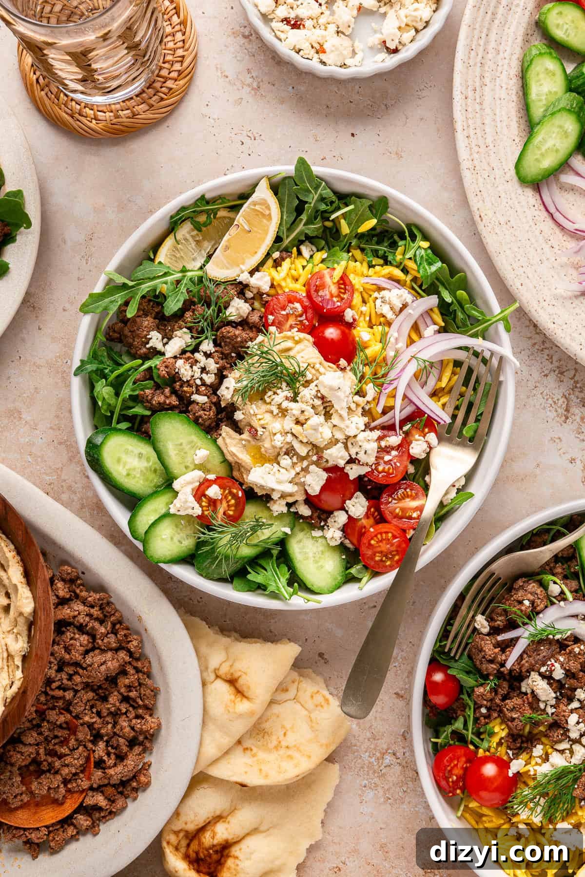 Two finished Ground Lamb Hummus Bowls served in white bowls. Pita and ground lamb are visible in the image as well.