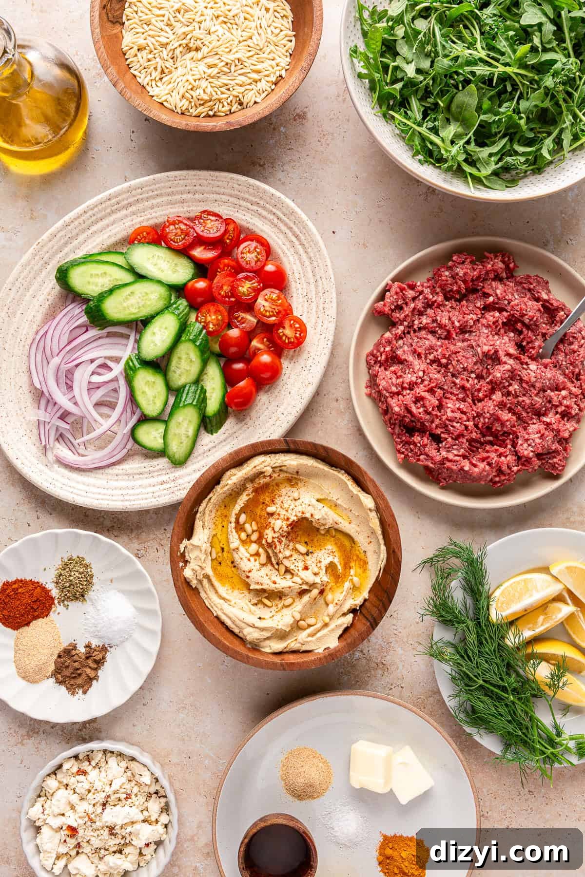 All the ingredients needed to make Ground Lamb Hummus Bowls, in various dishes and bowls, on a cream table.
