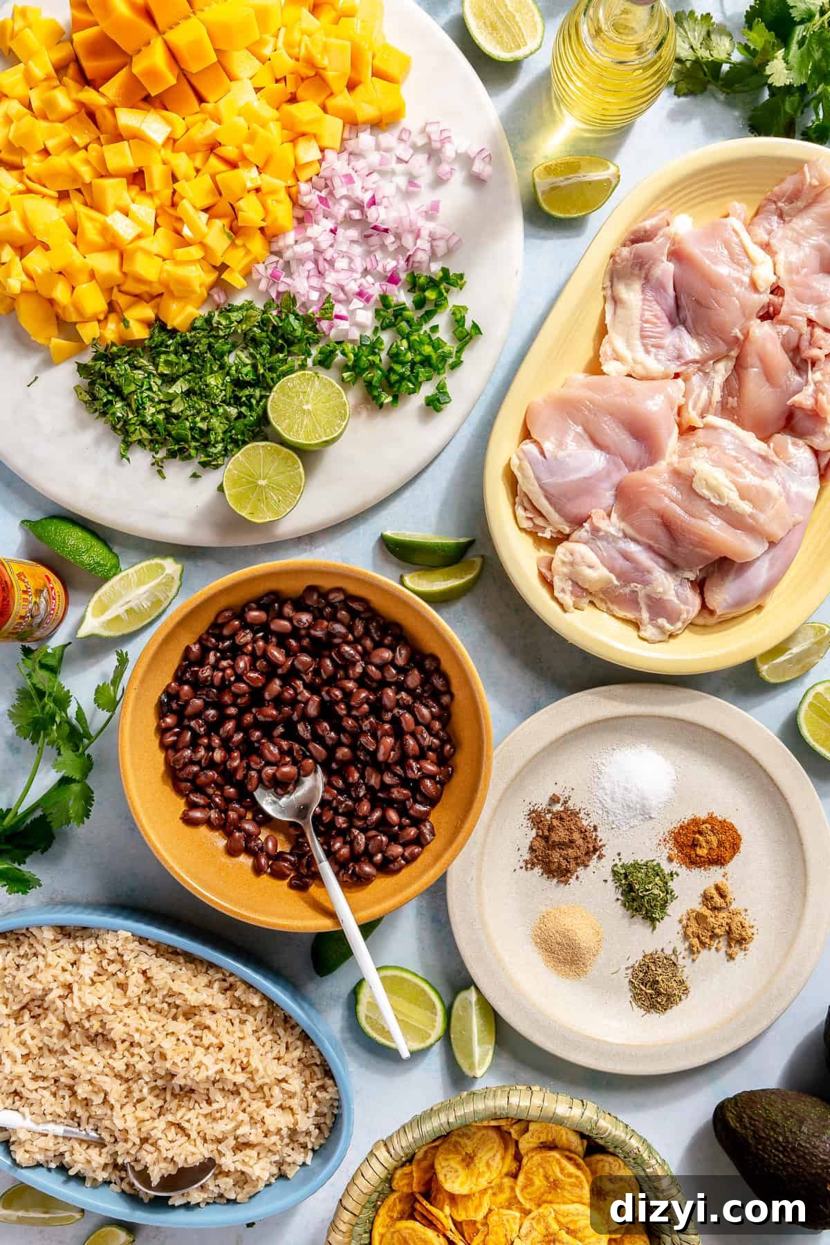 Caribbean Chicken Bowls with Jerk Seasoning and Mango Salsa 4 All of the ingredients needed to make Caribbean Inspired Chicken Bowls in various dishes on a white table.