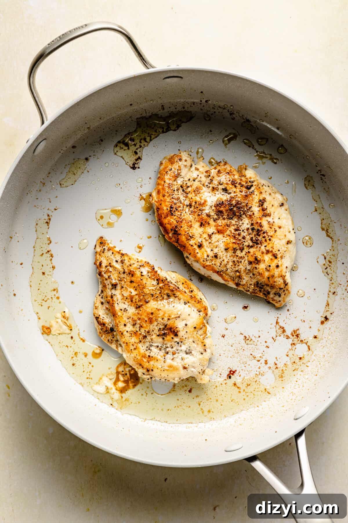 A skillet with oil and seasoned chicken cooking.