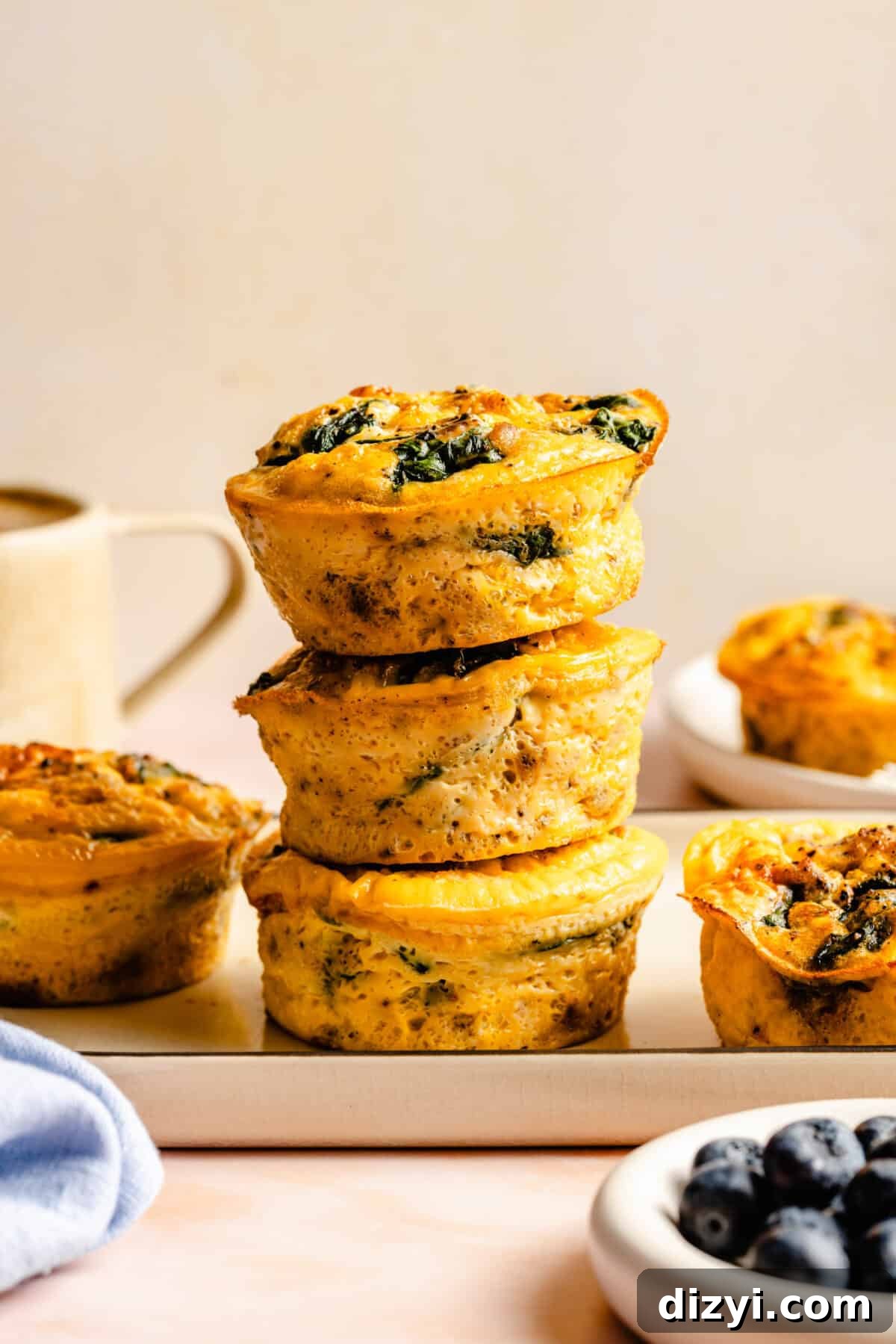 A stack of Sausage and Egg Mini Frittatas on a cream platter on a countertop.