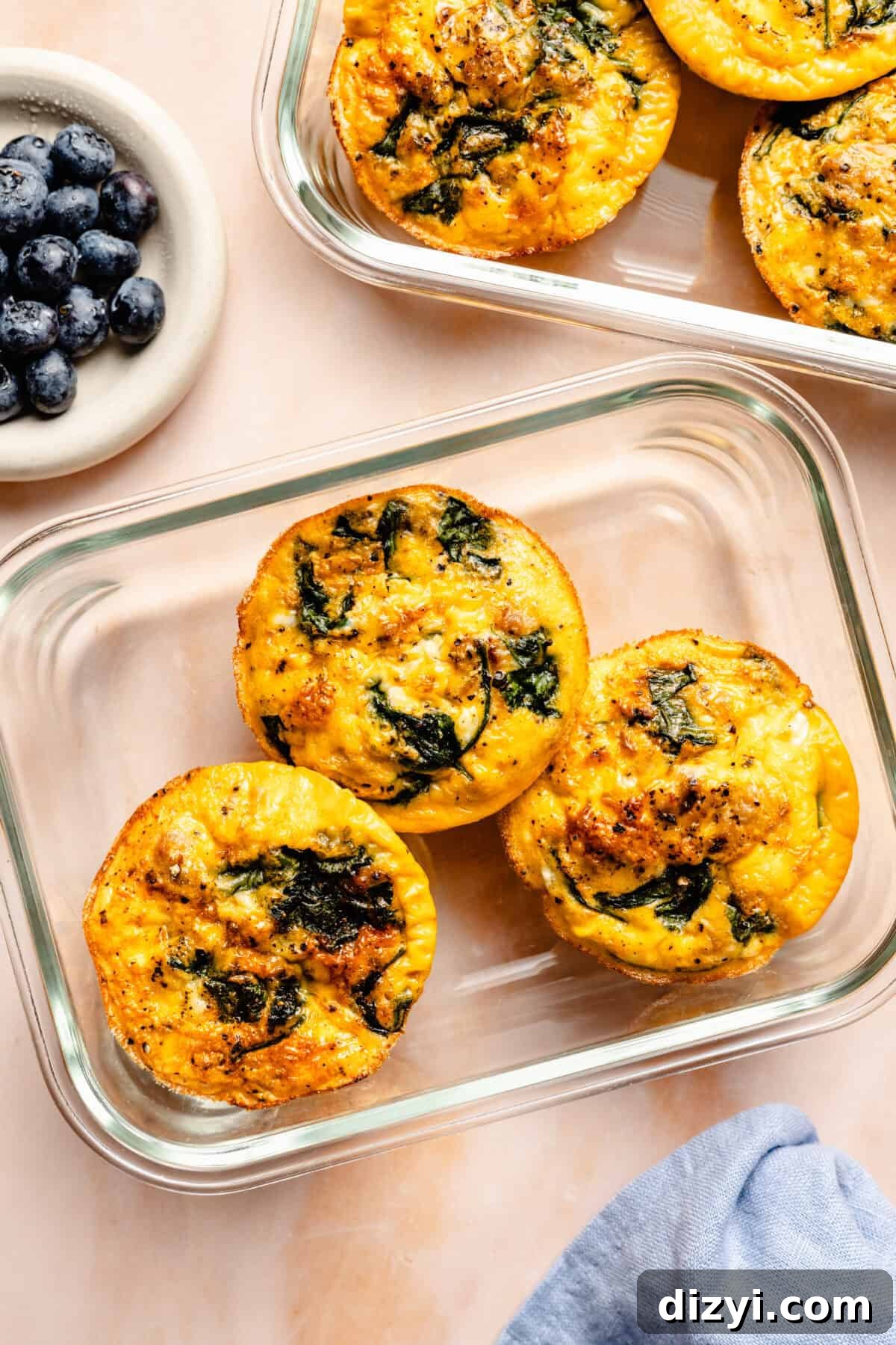 Three Sausage and Egg Mini Frittatas in the base of a clear airtight container ready for meal prep storage.