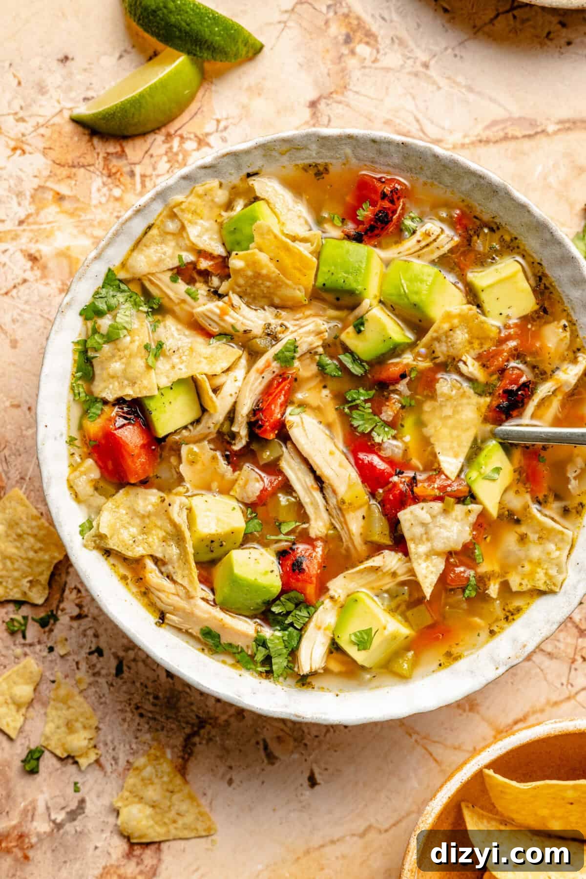 Sopa de Lima: Yucatan Lime Soup Recipe 2 A finished and garnished bowl of Sopa de Lima, in a white bowl, on an orange countertop.