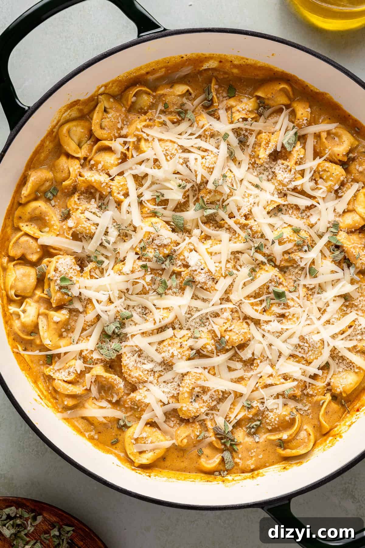 Creamy Pumpkin Tortellini in a skillet with cheese freshly added to the top of the tortellini.