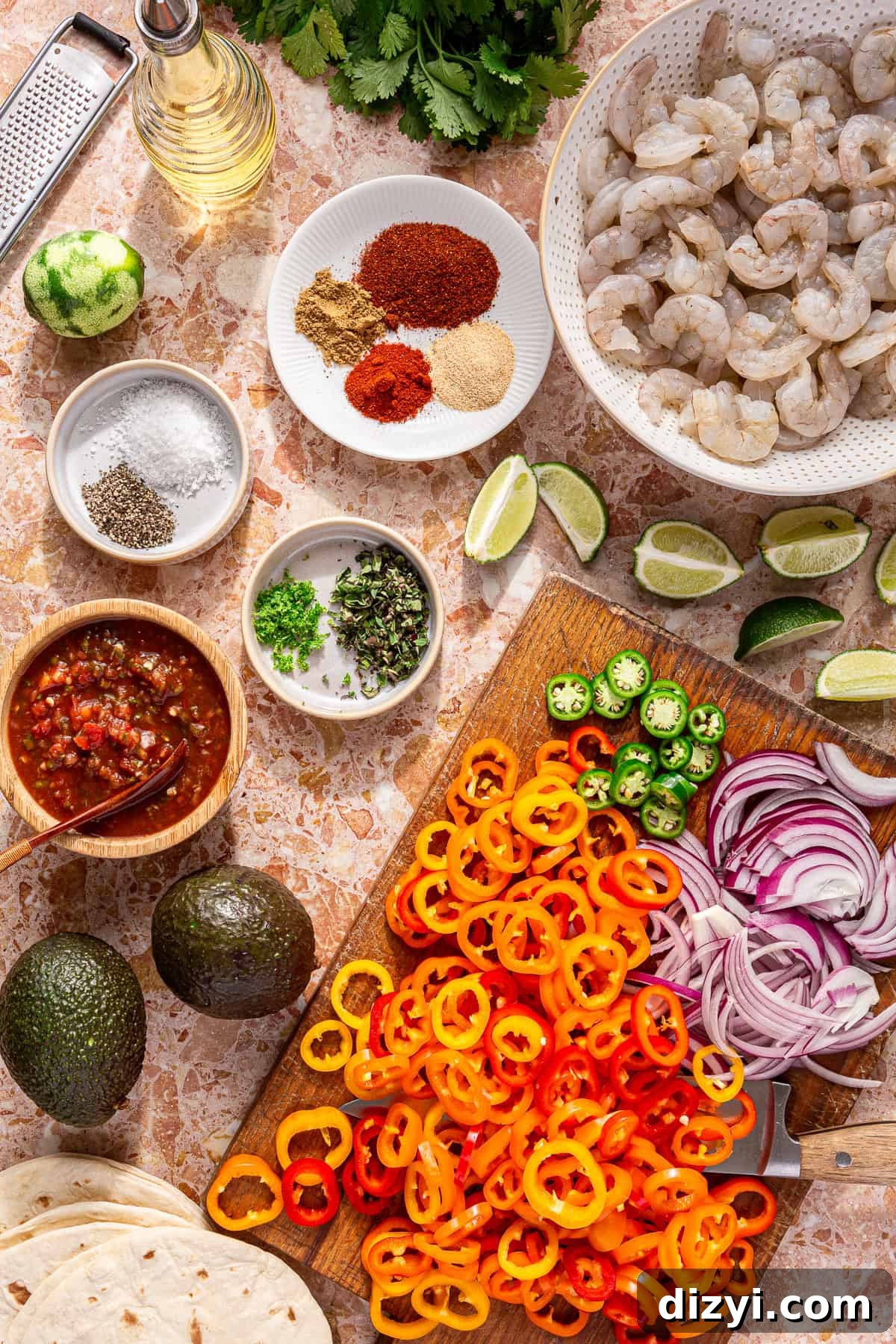 All of the ingredients needed to make Sheet Pan Shrimp Fajita Tacos in small dishes, bowls, and cutting boards.