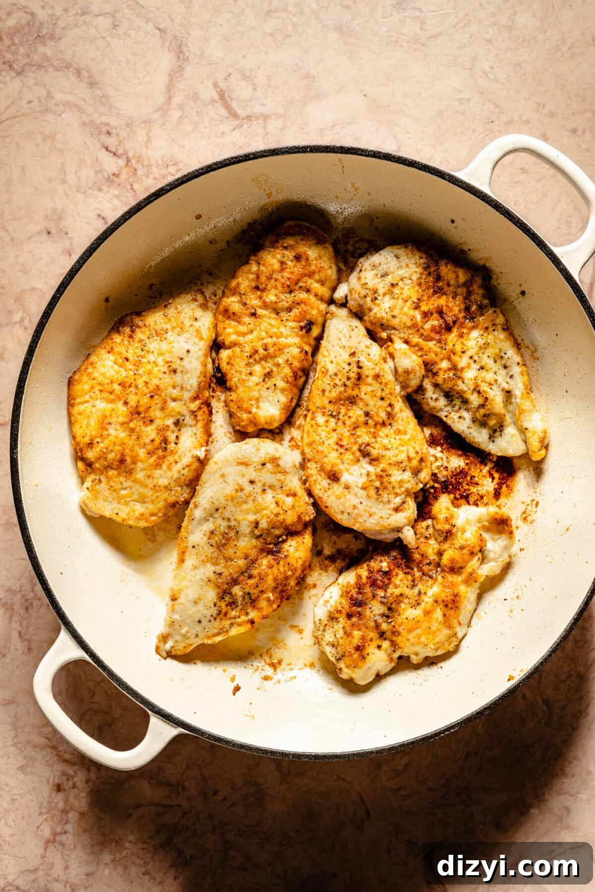 Chicken cutlets in a white skillet.