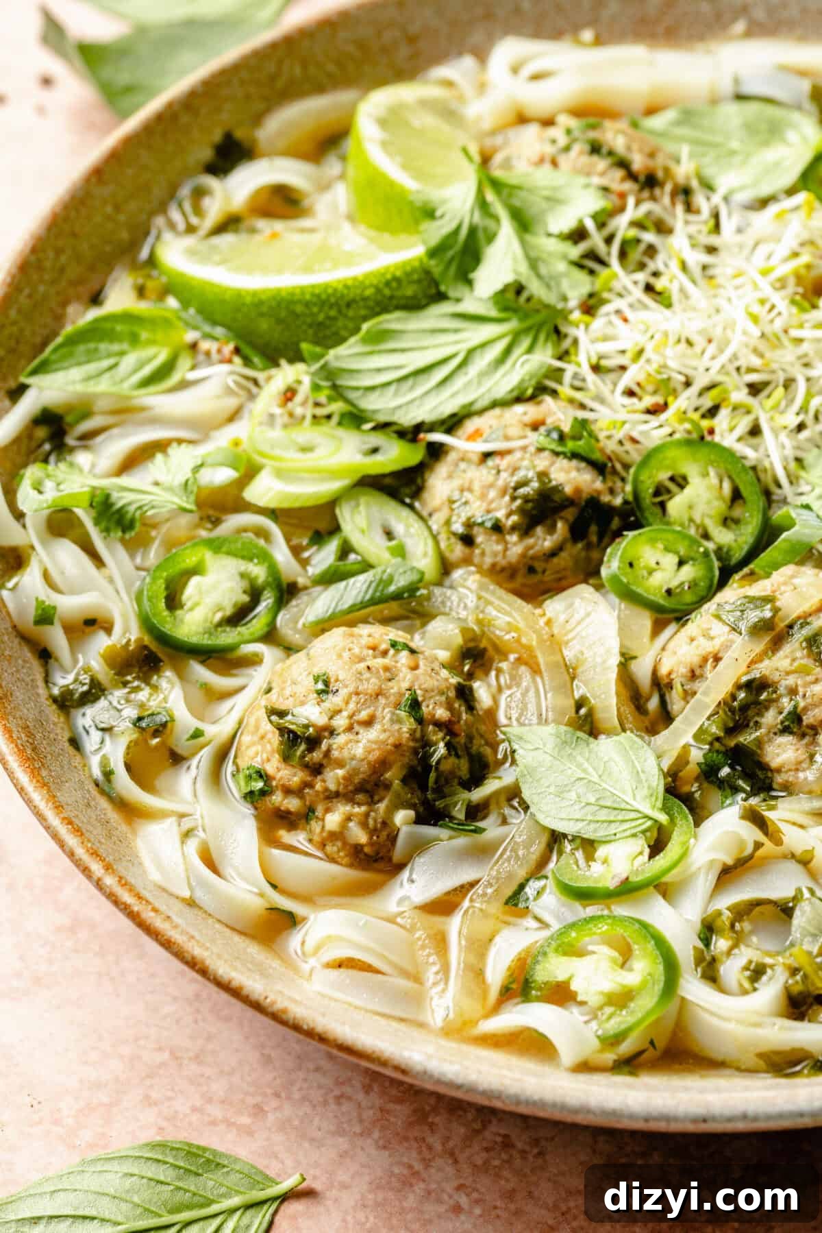 A close up shot of a finished bowl of Ginger-Pork Meatball Pho. A few basil leaves are visible in the image.