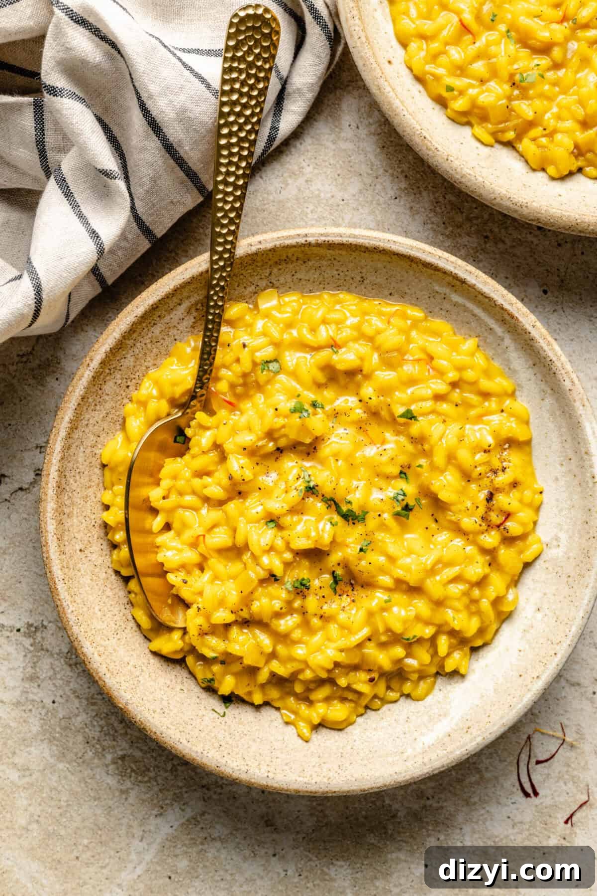 A close-up shot of a finished bowl of Risotto Milanese with a spoon and napkin.