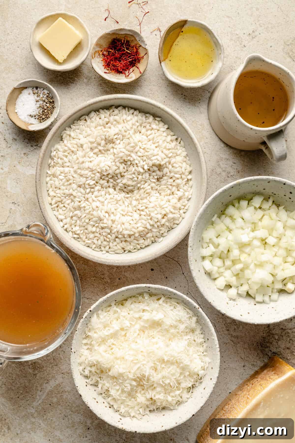 All of the ingredients needed for Risotto Milanese in various bowls and dishes on a tan countertop.