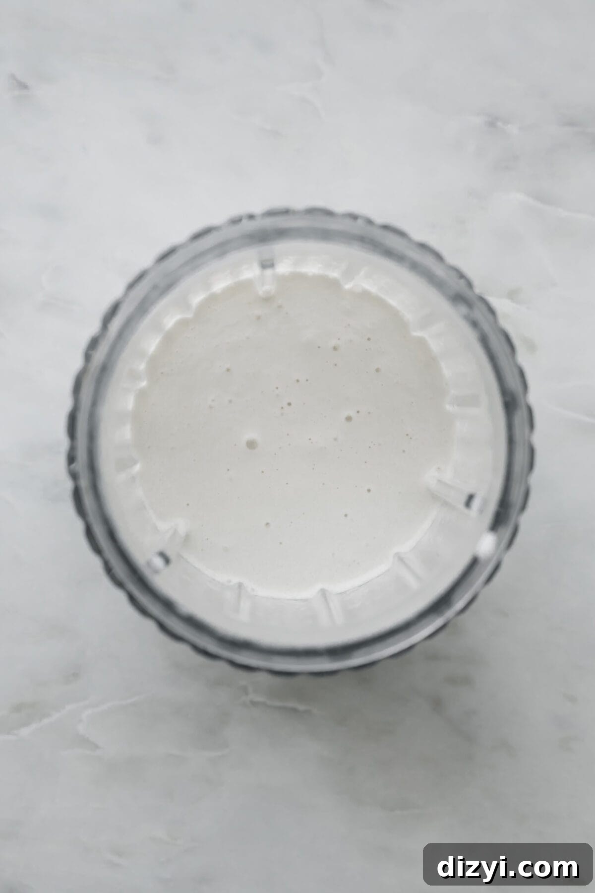 A freshly blended Brandy Freeze Cocktail in a clear blender cup on a white marble countertop, ready to be poured into the glass.