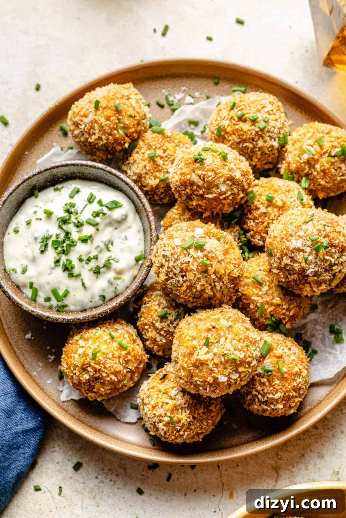 A finished plate of Crispy Crab Cake Bites on a cream countertop with a side of the tarragon aoili.